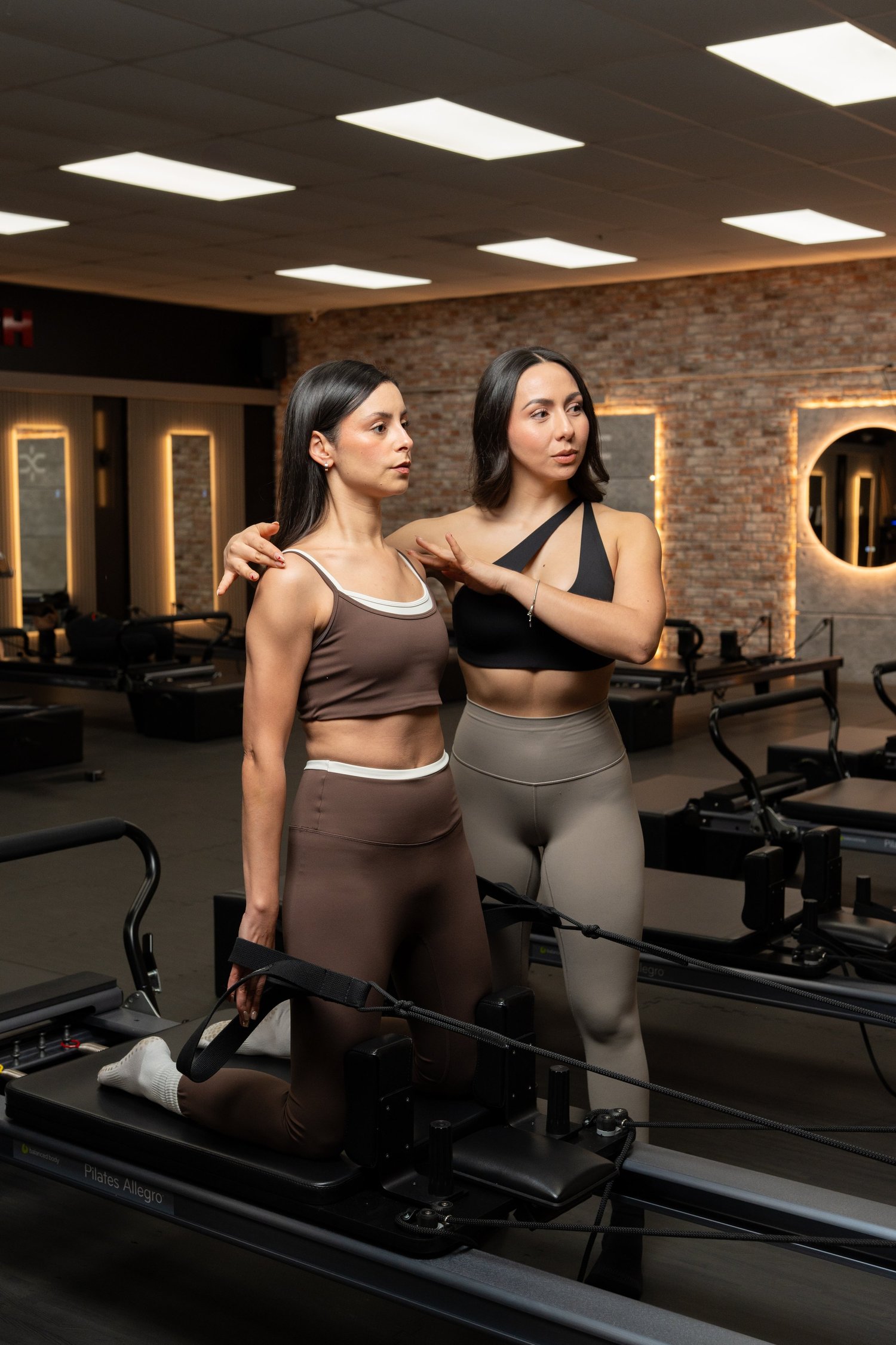 A coach guiding a member on a reformer at XFORM Pilates.